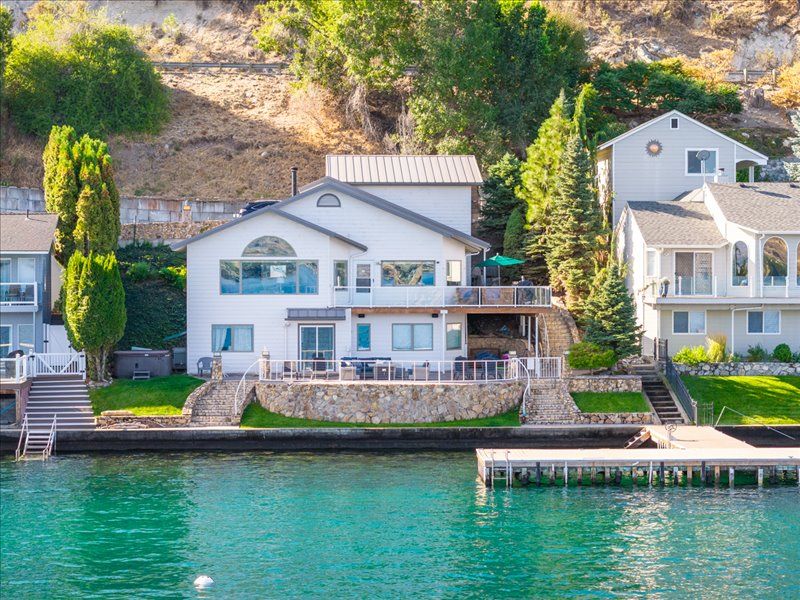Waterfront property with private dock on pristine lake, surrounded by lush hillside vegetation and mature trees.
